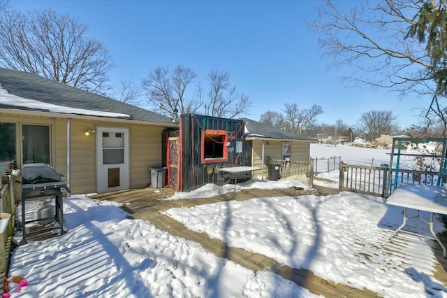 snow covered deck featuring area for grilling and fence