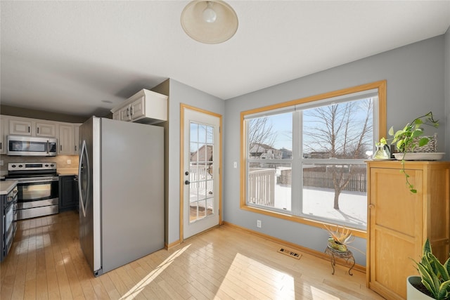 kitchen featuring light countertops, appliances with stainless steel finishes, light wood-type flooring, and white cabinetry