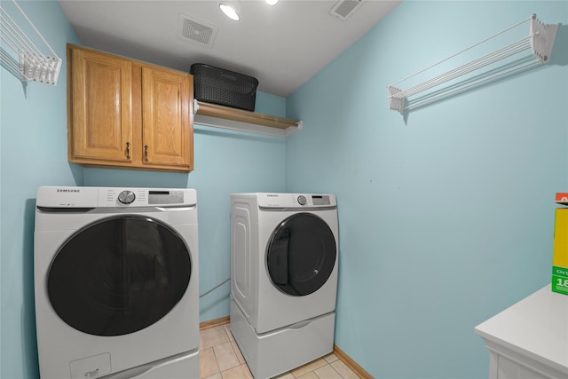 laundry area with washing machine and dryer, visible vents, cabinet space, and light tile patterned flooring