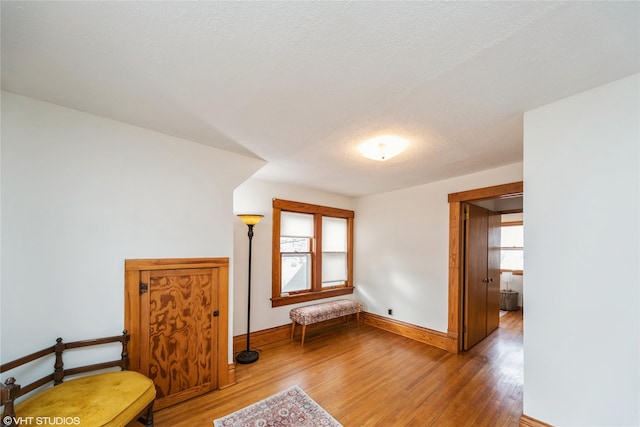 living area with plenty of natural light, a textured ceiling, baseboards, and wood finished floors