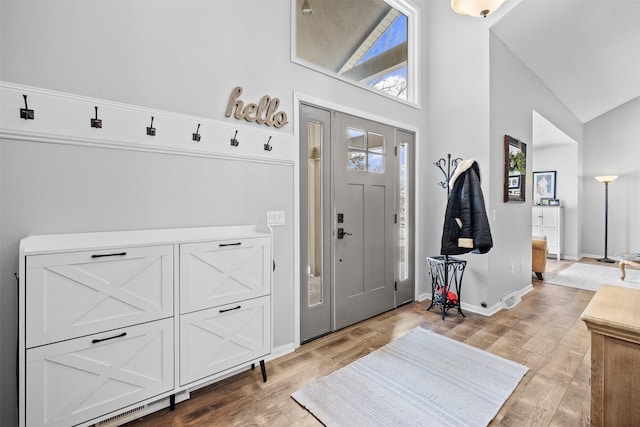 entryway with high vaulted ceiling, baseboards, and wood finished floors