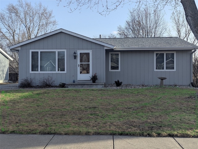 ranch-style home with a front lawn, board and batten siding, and roof with shingles