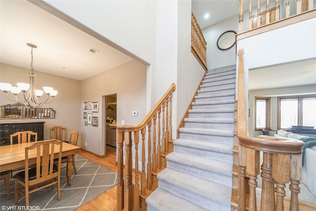 stairs featuring recessed lighting, baseboards, an inviting chandelier, and wood finished floors