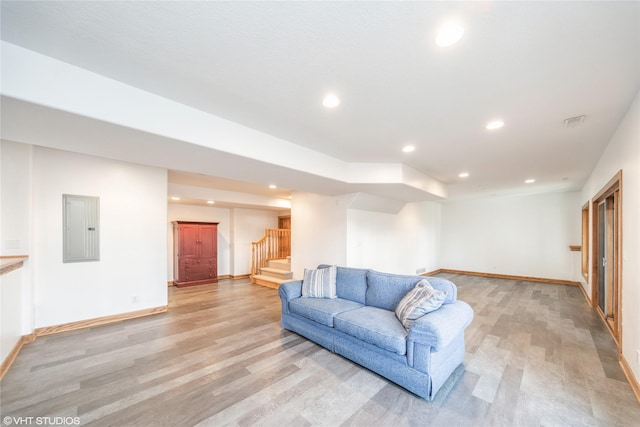 living room with light wood finished floors, stairway, electric panel, and recessed lighting