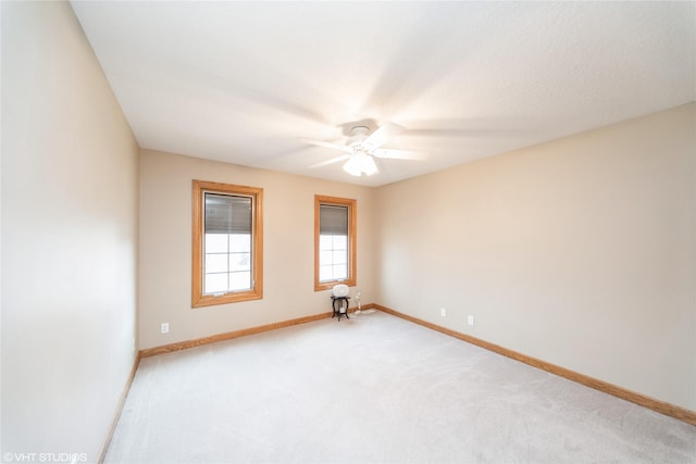 spare room featuring light carpet, ceiling fan, and baseboards