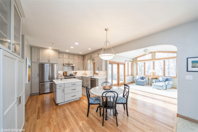 kitchen with appliances with stainless steel finishes, light countertops, decorative light fixtures, and gray cabinetry