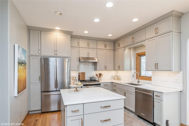 kitchen featuring stainless steel appliances, gray cabinets, a sink, and light stone counters