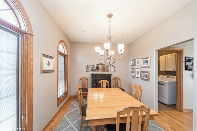 dining area featuring a chandelier, baseboards, light wood-style flooring, and washer and dryer