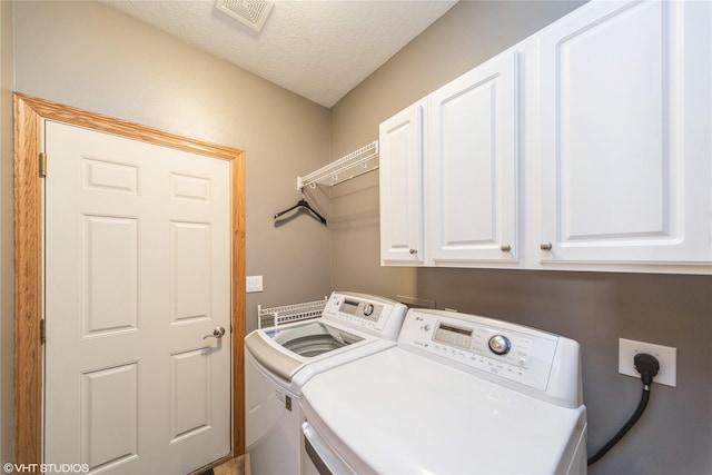 laundry area with a textured ceiling, visible vents, washing machine and dryer, and cabinet space