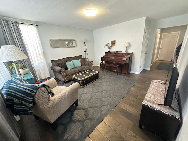 living area with dark wood-style flooring, a textured ceiling, and baseboards