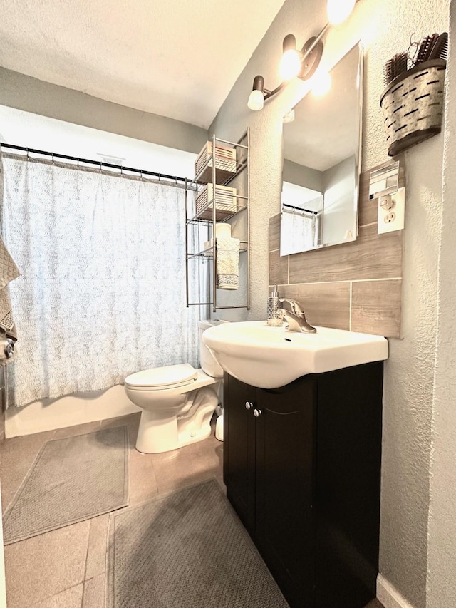 bathroom featuring decorative backsplash, a textured wall, toilet, tile patterned flooring, and vanity