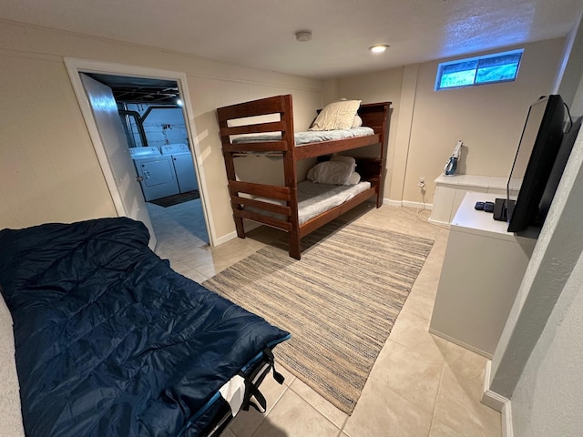 bedroom with baseboards, light tile patterned flooring, and washer and dryer