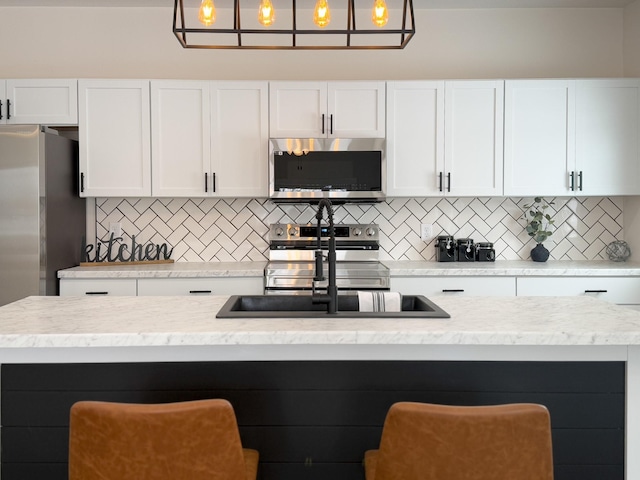 kitchen featuring appliances with stainless steel finishes, a breakfast bar, pendant lighting, and decorative backsplash