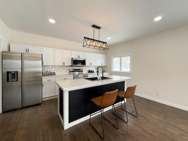 kitchen with white cabinets, a kitchen island with sink, stainless steel appliances, and light countertops