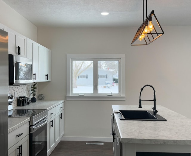 kitchen with hanging light fixtures, appliances with stainless steel finishes, light countertops, and white cabinets