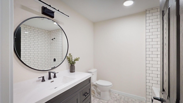 bathroom with toilet, a tile shower, and vanity