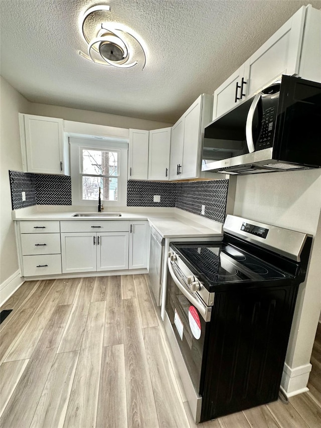 kitchen featuring stainless steel appliances, light countertops, and white cabinetry