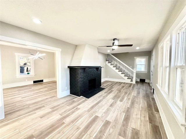 unfurnished living room featuring light wood-style flooring, a fireplace, stairway, and baseboards