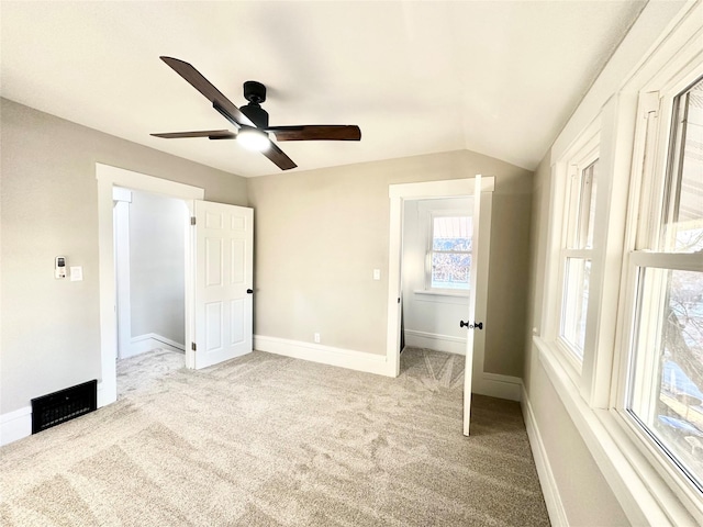 unfurnished bedroom featuring baseboards, vaulted ceiling, a ceiling fan, and light colored carpet