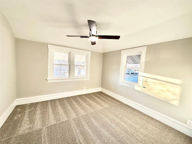 carpeted empty room with ceiling fan, vaulted ceiling, and baseboards