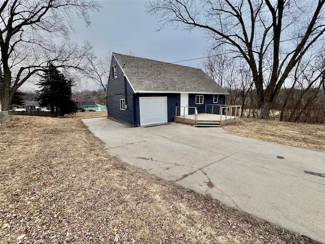 view of home's exterior with an attached garage, concrete driveway, and roof with shingles