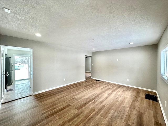 unfurnished room with baseboards, plenty of natural light, visible vents, and light wood finished floors