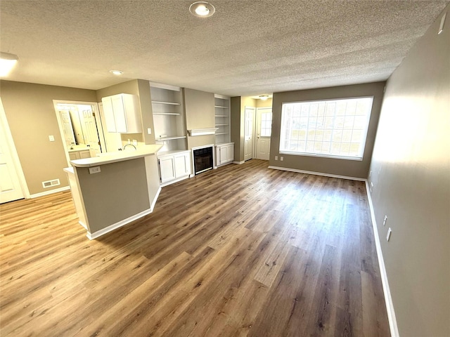 kitchen featuring a peninsula, wood finished floors, visible vents, white cabinetry, and light countertops