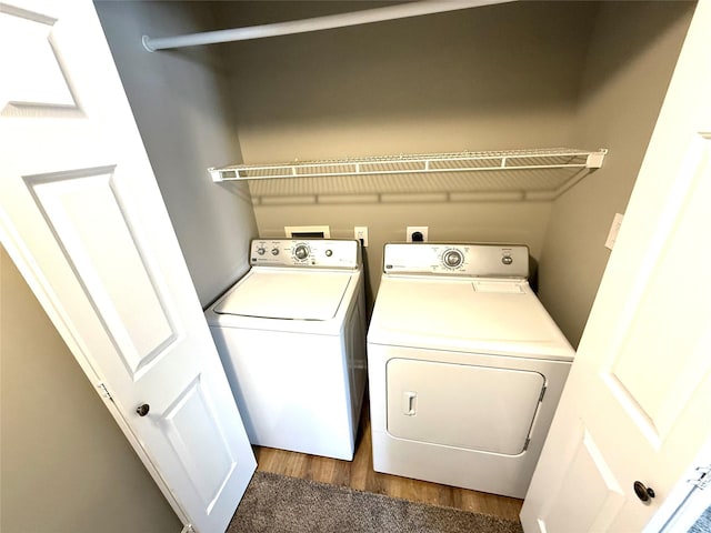 clothes washing area with laundry area, wood finished floors, and washing machine and dryer