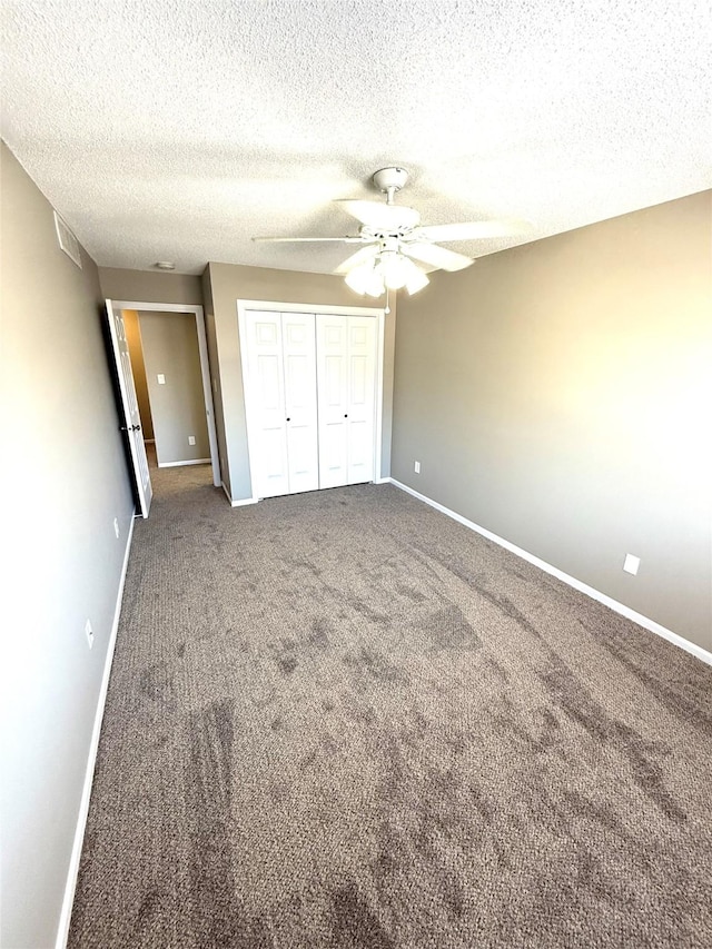 unfurnished bedroom featuring a textured ceiling, carpet floors, a ceiling fan, baseboards, and a closet