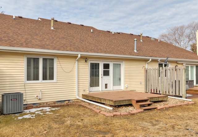 rear view of property with central AC unit, a lawn, a shingled roof, and a wooden deck