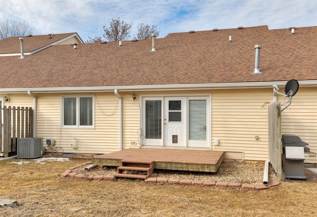 rear view of house featuring roof with shingles, a yard, a wooden deck, and central AC unit