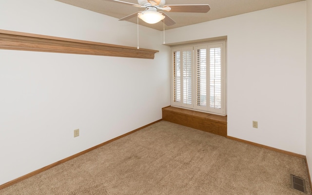 spare room featuring light colored carpet, visible vents, ceiling fan, and baseboards