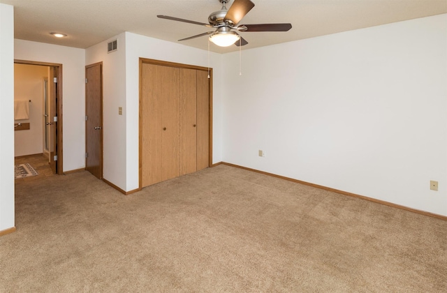 unfurnished bedroom featuring light carpet, baseboards, visible vents, ceiling fan, and a closet