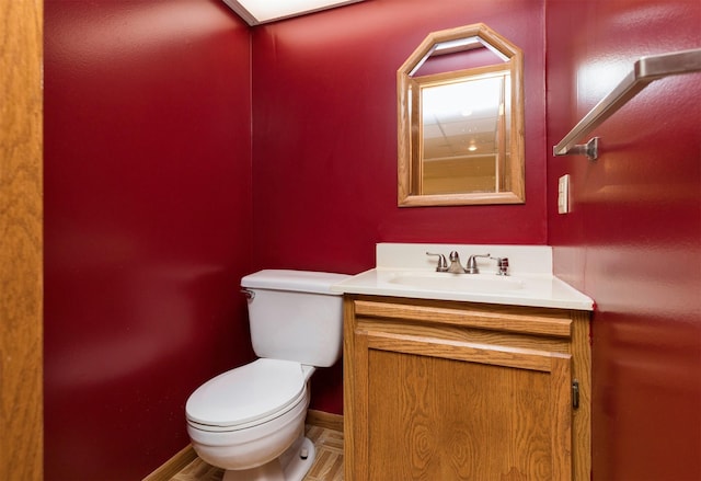 bathroom with toilet, baseboards, and vanity