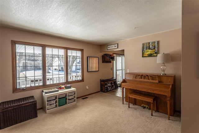 living area featuring visible vents, baseboards, a textured ceiling, and light colored carpet