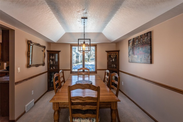 dining area featuring lofted ceiling, baseboards, visible vents, and light colored carpet