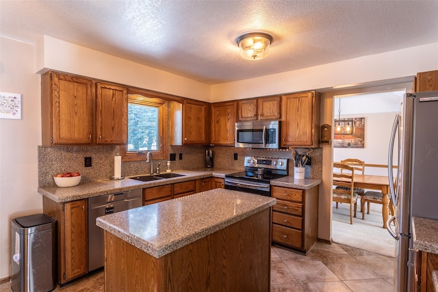 kitchen with decorative backsplash, brown cabinetry, appliances with stainless steel finishes, a center island, and a sink