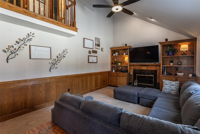 living room featuring visible vents, light colored carpet, a wainscoted wall, ceiling fan, and a fireplace