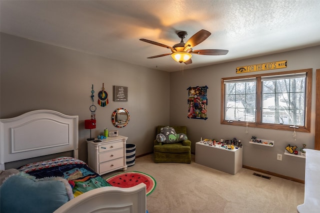 bedroom featuring a textured ceiling, light carpet, a ceiling fan, visible vents, and baseboards