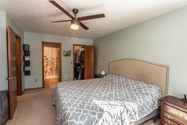 bedroom featuring a textured ceiling, light colored carpet, a ceiling fan, a spacious closet, and a closet