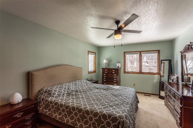 bedroom featuring light carpet, a textured ceiling, a ceiling fan, and baseboards