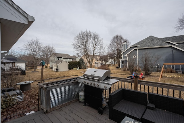 deck featuring a storage shed, a residential view, a grill, an outdoor structure, and a playground