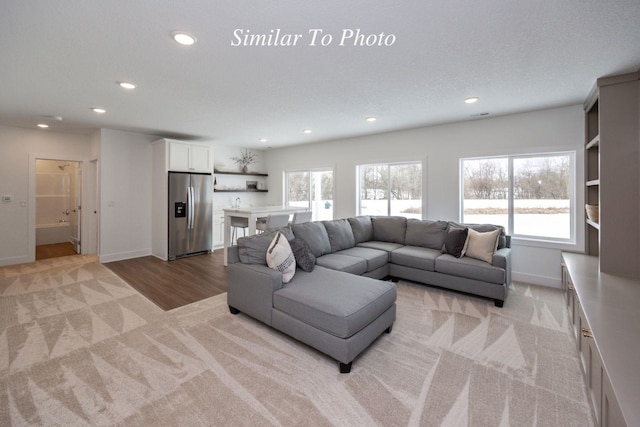 living room with light carpet, baseboards, a textured ceiling, and recessed lighting