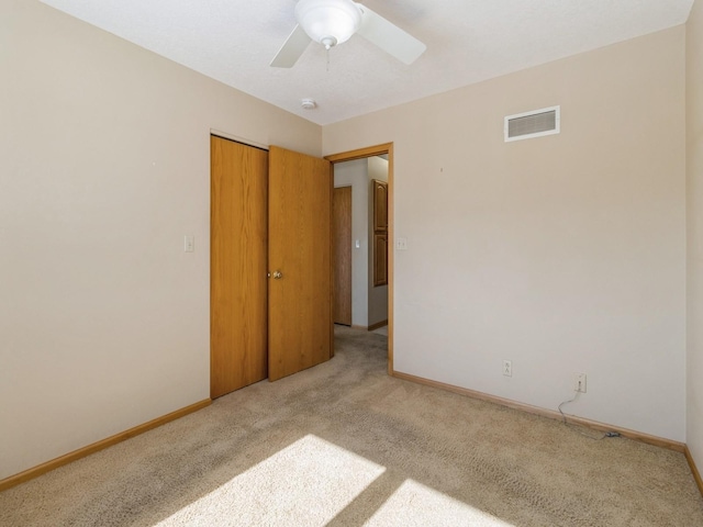 empty room with light carpet, a ceiling fan, visible vents, and baseboards