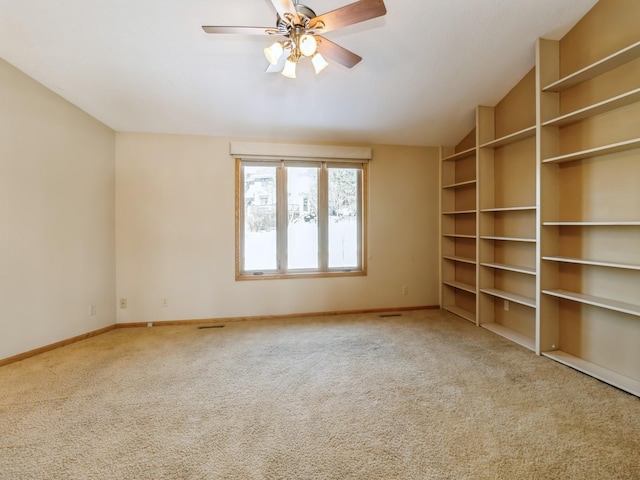 carpeted empty room featuring lofted ceiling, ceiling fan, visible vents, and baseboards