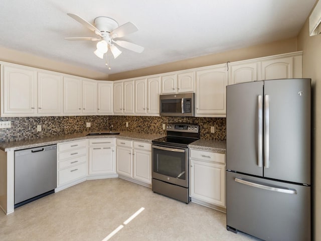 kitchen with ceiling fan, a sink, stainless steel appliances, white cabinetry, and backsplash