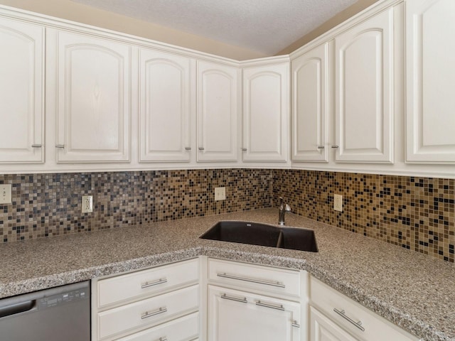 kitchen featuring black dishwasher, decorative backsplash, white cabinets, a sink, and a textured ceiling