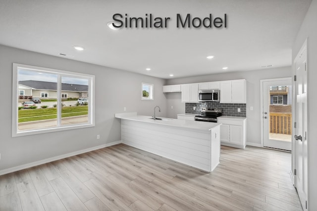 kitchen with white cabinets, a peninsula, stainless steel appliances, and light countertops