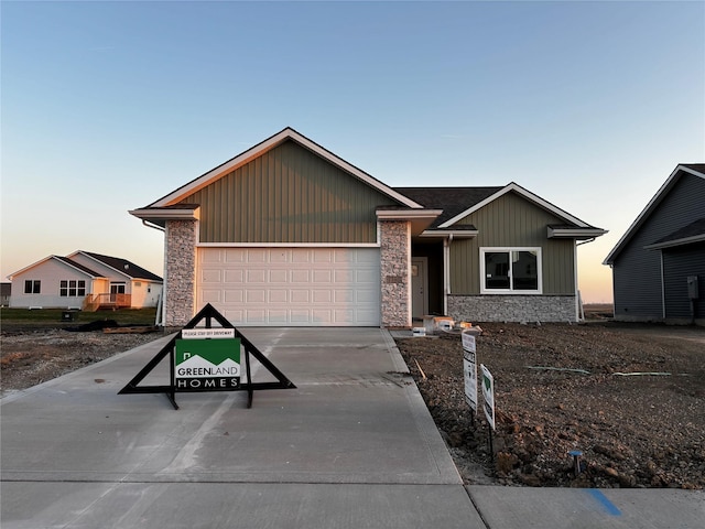 ranch-style home featuring driveway, a garage, and stone siding