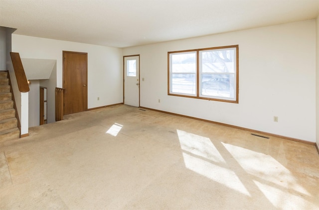 interior space with visible vents, stairway, baseboards, and light colored carpet